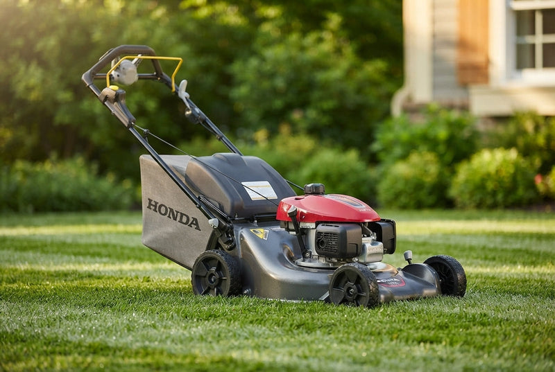 A Honda HRN216VKA walk-behind lawn mower on a neatly striped suburban lawn in a bright, sunny yard.
